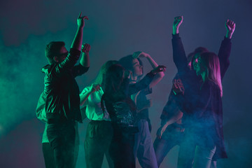 Cheering dance party, performance concept. Crowd shadow of people dancing with neon colorful lights raised hands up on dark background. Celebration, holiday, weekend, nightlife and positive vibes.