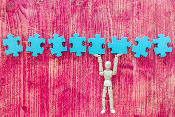 Wooden toy figure with puzzle on pink background - Powered by Adobe