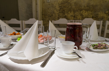 Banquet table, white napkins, elegant simple tableware. Coffee cup in the middle, salad bowl behind...