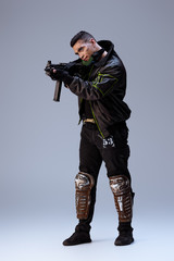 handsome bi-racial cyberpunk player aiming gun on grey