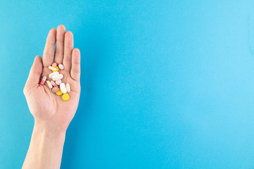 Fototapeta premium Hands hold a set of hygienic antiseptics and medications on a blue background.