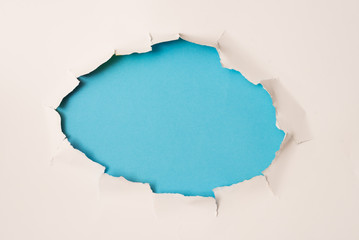 agujero rasgado en papel blanco y fondo azul