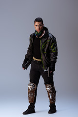 mixed race cyberpunk player with mask holding gun while standing on grey