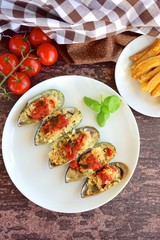Baked mussels with parmesan cheese, tomato sauce and basil. Served with French Fries. Seafood. Shellfish mussels. 