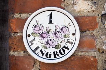 Close up of a vintage house number sign / plate on a red brick wall
