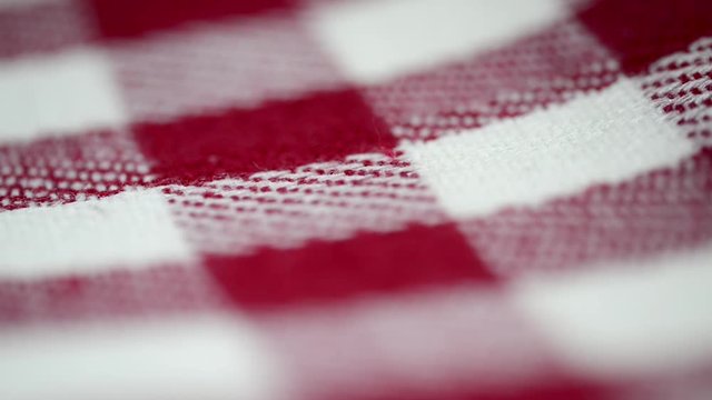 Red and white gridded tablecloth textil material close up slider footage.