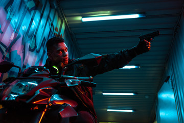 Fototapeta na wymiar selective focus of mixed race cyberpunk player on motorcycle aiming gun