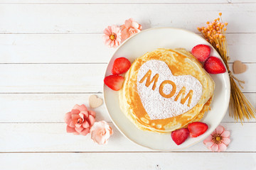 Pancakes with heart shape and MOM letters. Mothers Day breakfast concept. Overhead view against a...