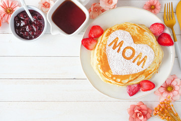 Pancakes with heart shape and MOM letters. Mothers Day breakfast concept. Above view corner border...
