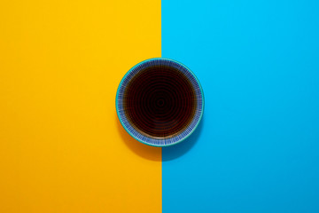 Dish with soy sauce on a blue and yellow background.