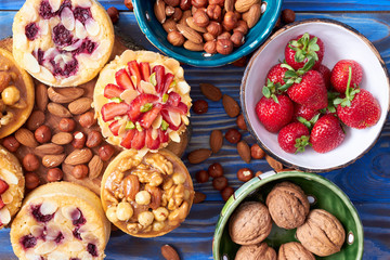 Mini tarts cupcakes with strawberries, walnuts, nuts and blueberries on blue wooden background. Top view. Close up