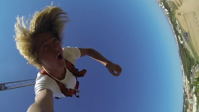 Young man with long blonde hair bungee jumping with a gopro in Lloret de Mar, Spain