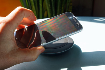 Smartfon odkładany na ładowarkę bezprzewodową. © Miroslaw