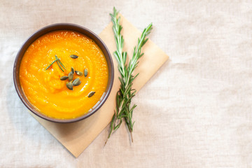 Pumpkin soup decorated on a table with a sprig of rosemary