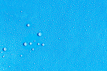 Water drops on light blue background, top view