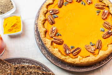 Pumpkin pie decorated with pecans on a served table for an autumn party food