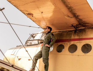 A handsome young pilot standing on the wing of a plane
