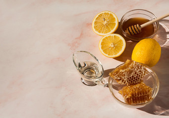 Natural home skin care. Ingredients for the mask. Sweet Golden honey, olive oil and lemon on a pink marble background. The soft sunlight. Free space. Copy space.