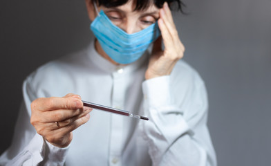 Coronavirus quarantine and Air pollution pm2.5 concept. Old sick woman wearing respirator mask for protect holds thermometer. Wuhan, China epidemic virus symptoms background.