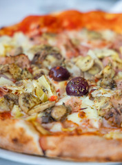 homemade pizza with ham, olives and artichoke