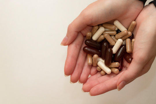 Female hand holds a tablet, capsule in hands. On white background. Pharmaceuticals. Allopathic medicine.
