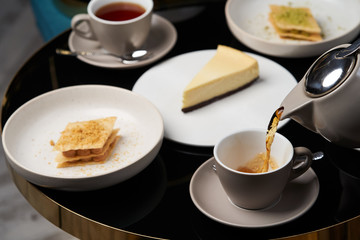 Woman hands with teapot pouring tea into cup, close-up