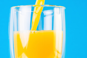 Glass of orange juice close-up on a blue background