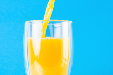 Full glass of orange juice on a blue background