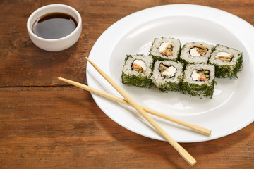 Rolls with salmon and dill on a white plate and soy sauce.