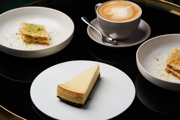 Cappuccino coffee cup and cake on plate on table, close-up.