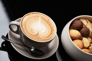 Sweet cookie snack and cappuccino coffee cup on table, close-up