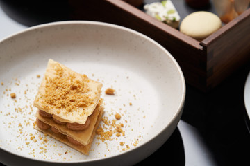 Cup of tea and slice of cheesecake on white plate on table