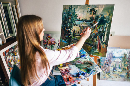 Girl artist paints an oil painting on canvas
