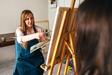 Woman artist paints a man from nature