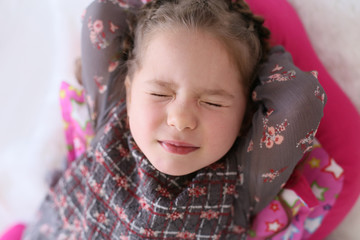 horizontal closeup portrait of a four year old girl lying on the floor with her eyes closed