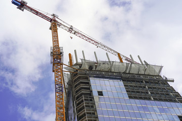 Skyscraper construction. Crane and building construction. Construction site with crane and a building against a cloudy sky.