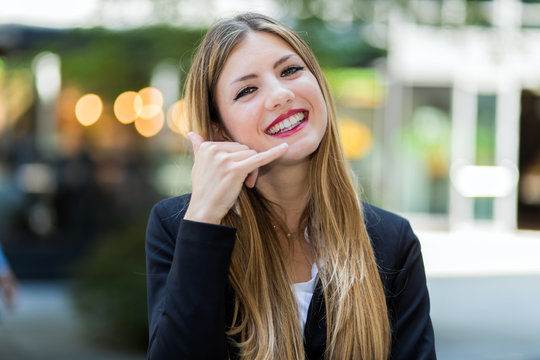 Business woman making a call me sign and smiling