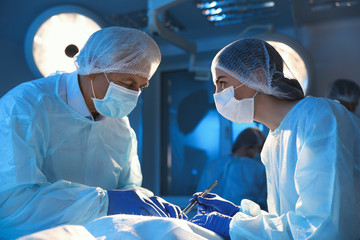 Team of professional doctors performing operation in surgery room