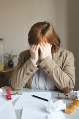Businesswoman strike with the fist on table. Businesswoman sitting with head in hands at desk covered crumpled papers. Entrepreneur who does not know what to do next with his business.