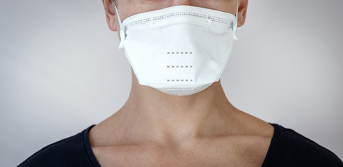 Young adult woman in white medical and protective face mask