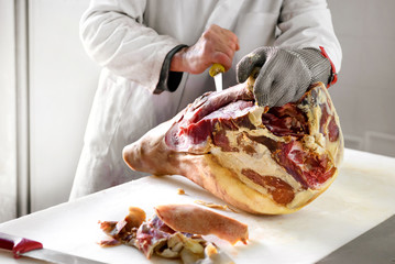 Obraz na płótnie Canvas Butcher works on ham, using metal glove