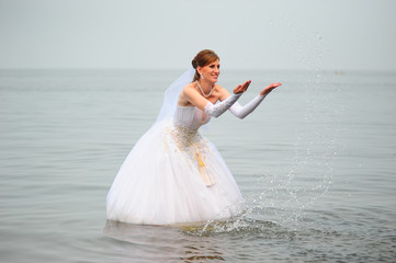 Fototapeta na wymiar Bride in a wedding dress on a wakeboard slides on the lake.