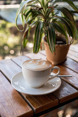Hot Latte with foam flower shape and plant decoration on wooden bar