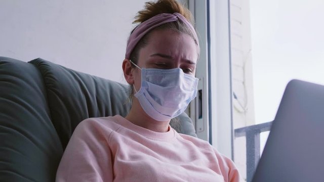 Young girl freelancer wearing protective mask while working from home.