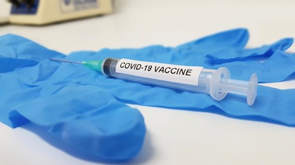 Coronavirus vaccine on blue protective glove