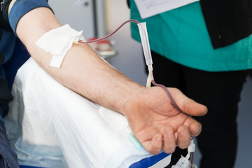 Close up arm of a man who donates blood. Male donor gives blood in a mobile blood donation center....