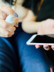 a girl in bed in quarantine time with a fever and running nose disinfecting her phone and camera 