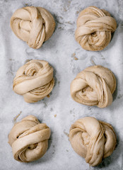 Ready to bake traditional Swedish cardamom sweet buns Kanelbulle on oven tray cover by baking paper. Flat lay, space