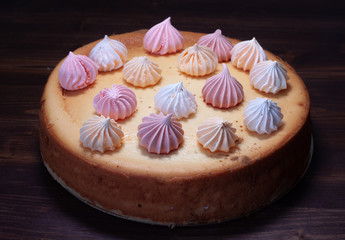 cheesecake decorated with meringue on a wooden table