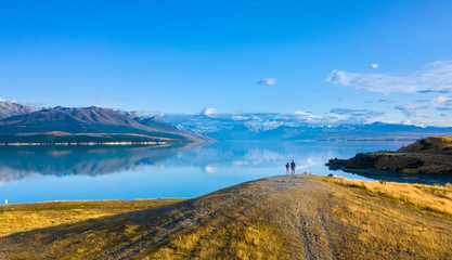 Viewpoint at sunrise where two young people enjoying the beautiful view of the calm lake and snowy  mountains in the back